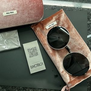 Miu Miu round large silver frame and black lens sunglasses.